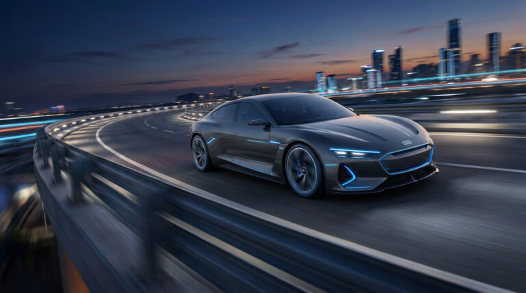 Une voiture concept Audi électrique grise avec des accents lumineux bleus circulant sur un pont urbain la nuit.