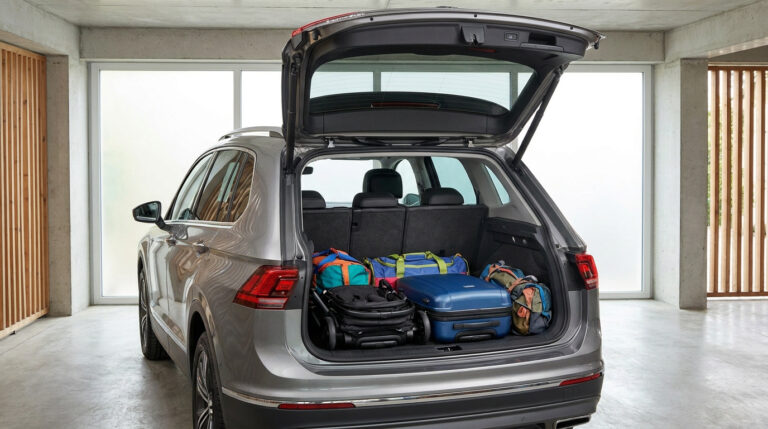 Coffre ouvert d'un SUV gris rempli de bagages et d'une poussette, stationné dans un garage moderne.