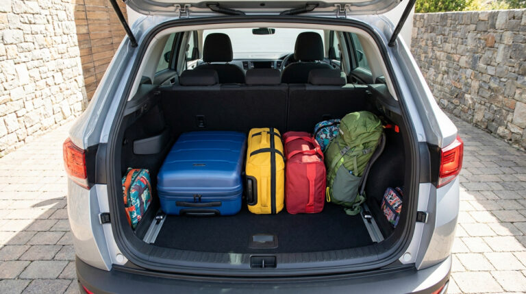 Coffre ouvert d'un Renault Captur chargé de bagages, sacs et valises disposés sur la banquette arrière.