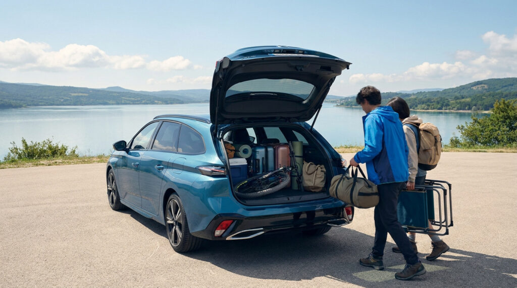 Couple chargeant des bagages et du matériel de camping dans le coffre ouvert d'une Peugeot 308 SW au bord d'un lac.