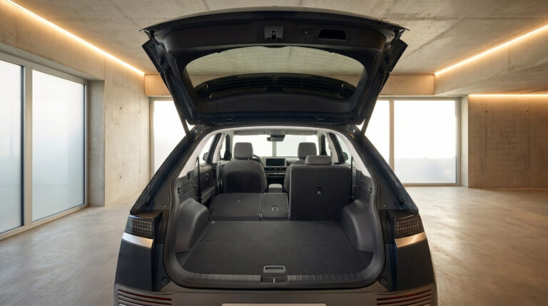 Coffre ouvert du Hyundai Ioniq 5 avec les sièges arrière partiellement rabattus dans un garage moderne.